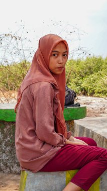 Kurak mevsimin arka planında tesettür takan bir Cava kadınının güzel görünüşü. 