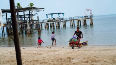 Jepara, Central Java 'dan. 3 Ekim 2023 - Deniz üzerindeki kafenin güzel manzarası ve plajda oynayan insanlar. 