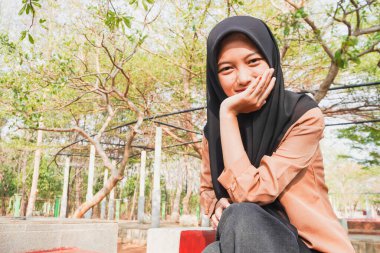 Başörtüsü takan Cava 'lı bir kadının güzel görünüşü gözlerini gökyüzüne dikmiş oturuyor.. 