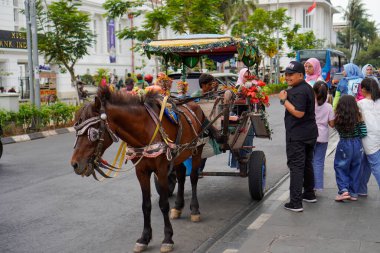 Jakarta eski şehir, 19 Aralık 2023. Yolcu taşımak için yolun kenarında duran bir at arabası. 