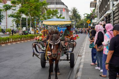 Jakarta eski şehir, 19 Aralık 2023. Yolcu taşımak için yolun kenarında duran bir at arabası. 