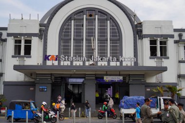 Jakarta Eski Şehir, 19 Aralık 2023. Tren istasyonunun önünden geçen insanlar..