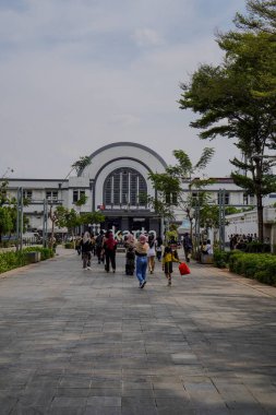 Jakarta Eski Şehir, 19 Aralık 2023. Tren istasyonunun önünden geçen insanlar.. 