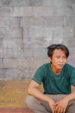 Yakışıklı adam merdivenlerde oturuyor doğal bir taş duvarın arka planında..