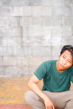 Yakışıklı adam merdivenlerde oturuyor doğal bir taş duvarın arka planında..