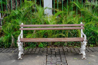 Klasik bir model ve bankın arkasında bitkiler olan silahlı bir bahçe tezgahı..