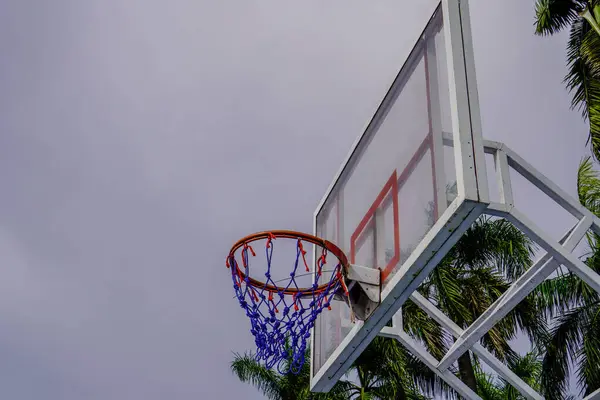 Close-up view of a basketball basket against a cloudy sky background.