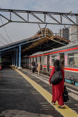 jakarta, januari 30, 2024 - elektrikli trenin yanında yürüyen kadın.