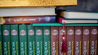 Kur 'an' ın bir kitaplığa düzgünce yerleştirilmiş yakın plan görüntüsü.