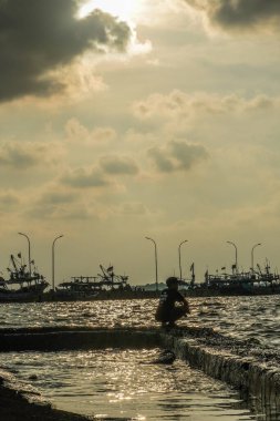 Jepara, Central Java, 7 Nisan 2024 - Jepara rıhtımında gün batımında gökyüzü olan balıkçılar fotokopi için boş alan. Reklam için doğa kavramı.