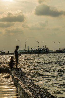 Jepara, Central Java, 7 Nisan 2024 - Jepara rıhtımında gün batımında gökyüzü olan balıkçılar fotokopi için boş alan. Reklam için doğa kavramı.