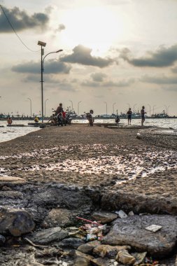 Jepara, Central Java, 7 Nisan 2024 - Jepara rıhtımında gün batımında gökyüzü olan balıkçılar fotokopi için boş alan. Reklam için doğa kavramı.