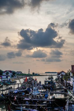 Jepara, Central Java, 7 Nisan 2024 - Jepara balıkçı tekneleri kalabalık bir limana park etti akşam gökyüzünün arka planına doğru boş bir reklam alanı ile