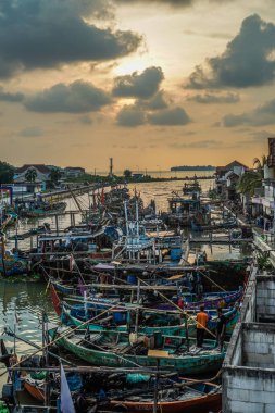 Jepara, Central Java, 7 Nisan 2024 - Jepara balıkçı tekneleri kalabalık bir limana park etti akşam gökyüzünün arka planına doğru boş bir reklam alanı ile