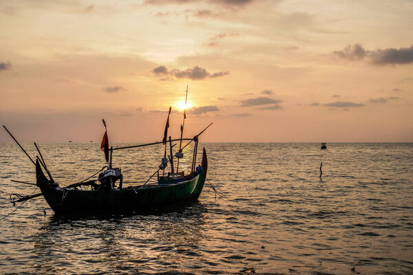 fishing boats on the sea against an orange sky at night with empty space for photocopies.