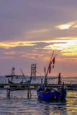 Balıkçı tekneleri deniz kenarındaki rıhtımda izole edilmiş turuncu bir gökyüzü arka planı ve fotokopi için boş bir alanı var..