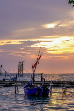 Balıkçı tekneleri deniz kenarındaki rıhtımda izole edilmiş turuncu bir gökyüzü arka planı ve fotokopi için boş bir alanı var..
