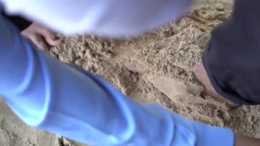 Sahildeki beyaz kumda oynayan peçeli bir kadının üst görüntüsü..