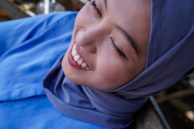 Gülümseyen bir ifadeyle tesettürlü Müslüman kadının yüzüne yakından bakın..