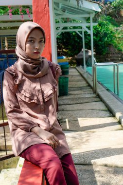 Yüzme havuzunda rahatça oturan Müslüman bir kadının yakın plan görüntüsü..