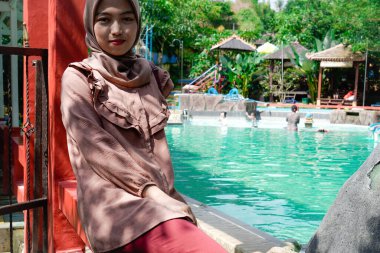 Yüzme havuzunda rahatça oturan Müslüman bir kadının yakın plan görüntüsü..