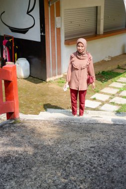 Başörtüsü takan Cava 'lı kadın parkta güneş ışığının arka planında yürüyor..