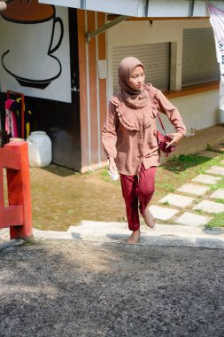 Başörtüsü takan Cava 'lı kadın parkta güneş ışığının arka planında yürüyor..