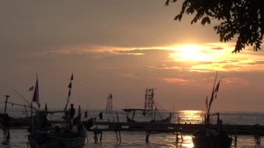 Bir grup balıkçı teknesi gece vakti turuncu gökyüzünün arka planıyla rıhtıma yanaştı..