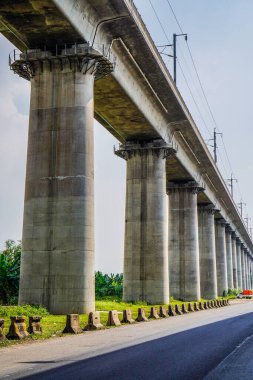 Beton destekli bir elektrikli tren yolunun alt görünümü, kopyalama alanı olan gökyüzü arkaplanı.