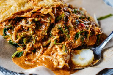 Fıstık soslu karışık sebzelerden oluşan pekel tabağı ve Endonezya 'nın tipik bir gıda konsepti olan lontong pilavı ile servis ediliyor..