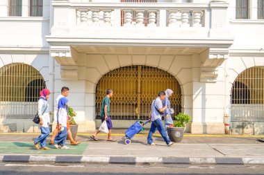 old city of jakarta, july 20, 2024- Asian people walking on the sidewalk against the backdrop of classic old building doors in the old city of Jakarta. clipart