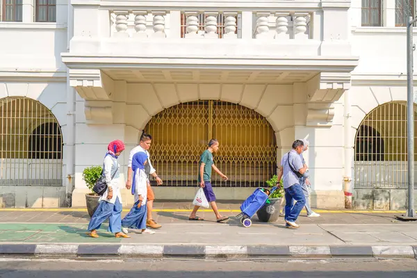 stock image old city of jakarta, july 20, 2024- Asian people walking on the sidewalk against the backdrop of classic old building doors in the old city of Jakarta.