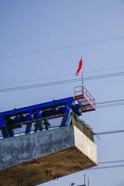 Üst geçitteki inşaat sahasında arka planda boş bir boşlukla gökyüzüne bakan demiryolu kazıkları var..