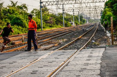 Ancol, Kuzey Jakarta, 10 Ağustos 2024, demiryolu geçiş görevlileri geçen elektrikli trenler üzerinde nöbet tutuyorlardı.. 