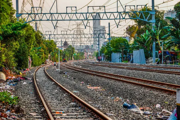 Raylar boyunca elektrik direkleri olan bir tren yolu manzarası.