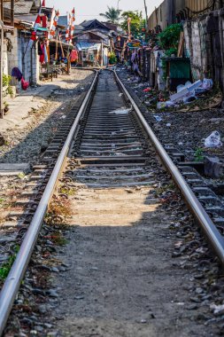 Raylar boyunca elektrik direkleri olan bir tren yolu manzarası.