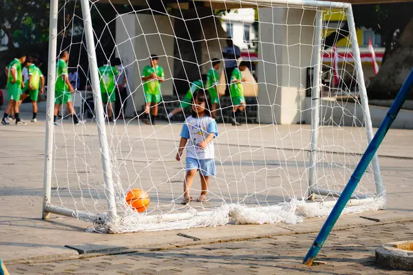 Pamulang, Güney Tangerang, 9 Ağustos 2024, kalede tek başına top oynayan küçük çocuk, kalenin arkasından bakıyor..