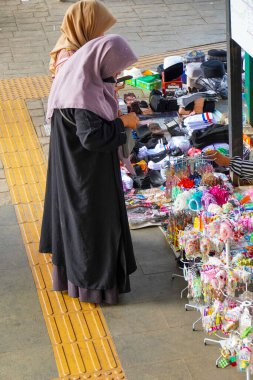 Merkez jakarta, 17 Ağustos 2024, başörtüsü takan iki kadın kaldırımda satılan malların önünde dikiliyordu..