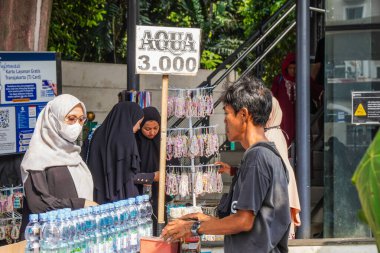 Merkez jakarta, 17 Ağustos 2024 maden suyu satan bir adamın davranışı başörtüsü takan Asyalı bir kadına hizmet etmektir.