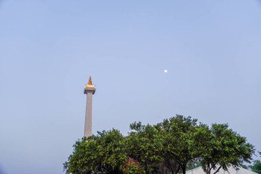 Jakarta, August 17, 2024, monument with the shape of a burning fire torch against the background of the moon in the blue sky. clipart