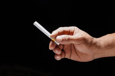Kopyalama alanı için siyah arka planda bir sigarayı tutan el, sigarayı tutan el kapağı..
