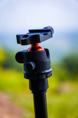 Bulanık arkaplanı olan bir tripoda yakın plan, bulanık yeşil çimenlikte tripoda yakın çekim