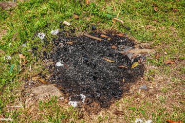 Çimenlerin üzerinde izole edilmiş yanık kalıntıları, siyah çimenler ve yeşil çimlerin üzerinde kömür kalıntıları..