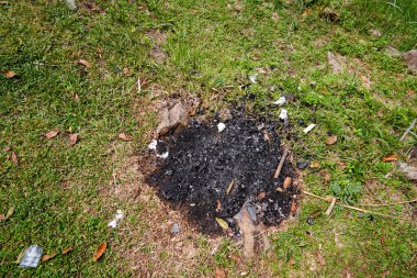 Çimenlerin üzerinde izole edilmiş yanık kalıntıları, siyah çimenler ve yeşil çimlerin üzerinde kömür kalıntıları..