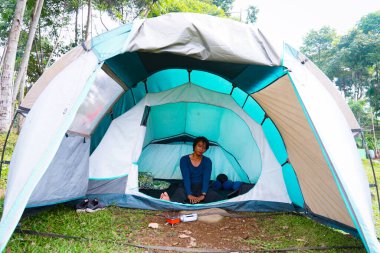 Asyalı adam tatilde kamp çadırında uyuduktan sonra uyandı..