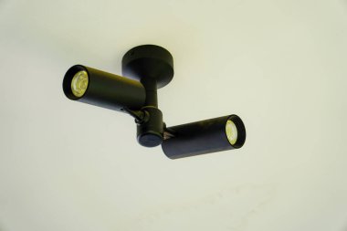 Evin tavanında modern spot ışıkları. İki döner spot ışığı. Spot ışıkları sarkmış. Siyah metal ışıklar reklam için boş alana yakın görünüyor.