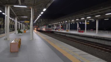 Matraman, Doğu Jakarta, 21 Ağustos 2024, İstasyonlarda hareket eden ve duran elektrikli trenler, Matraman tren istasyonuna gelen modern kırmızı bir lokomotif kabini dikey ön görüş, konsept