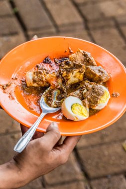 Siomay 'ı tabakta fıstık sosuyla tutan adamın yan görüntüsü lezzetli görünüyor, tipik Endonezya yemeği.