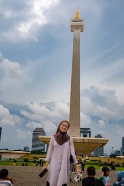 Merkez jakarta, 25 Aralık 2024, tesettürlü Asyalı kadın kameraya bakıyor ve arka planda parlak bir gökyüzü, boş bir fotokopi alanı olarak görülüyor..