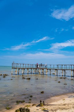Denizde güzel bir ahşap iskele manzarası, sahilde ahşap iskelede yürüyen insanlar, ahşap iskelede şakalaşıp denize bakan türbanlı kadınlar.